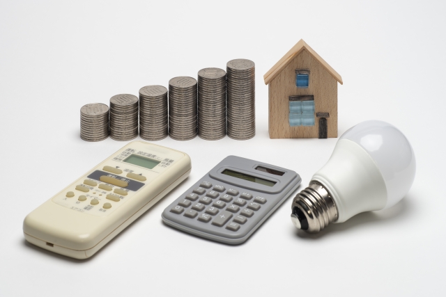家計と省エネをイメージした電卓・LED電球・硬貨と家模型
