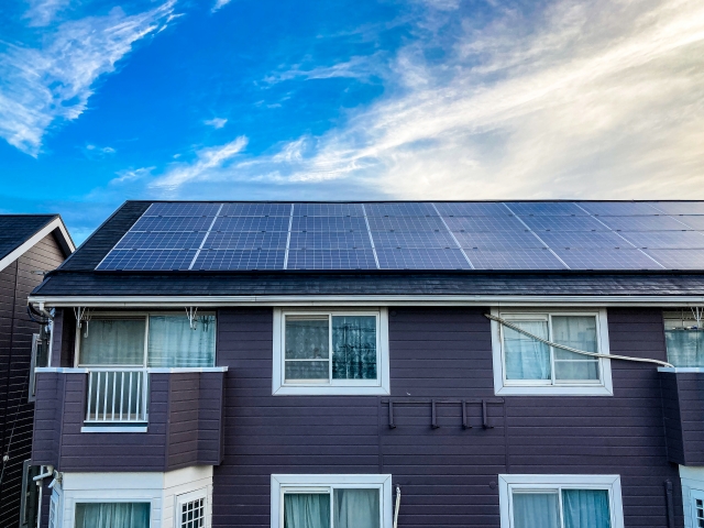 青空の下、屋根に太陽光パネルを設置した住宅