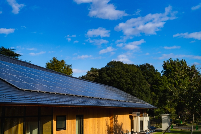 木造住宅の屋根に設置された太陽光発電パネルと青空
