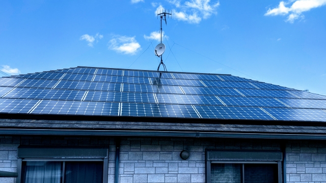 住宅の屋根に設置された太陽光発電パネルと青空の風景
